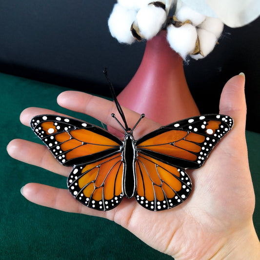 Monarch butterfly stained glass suncatcher hanging in a window